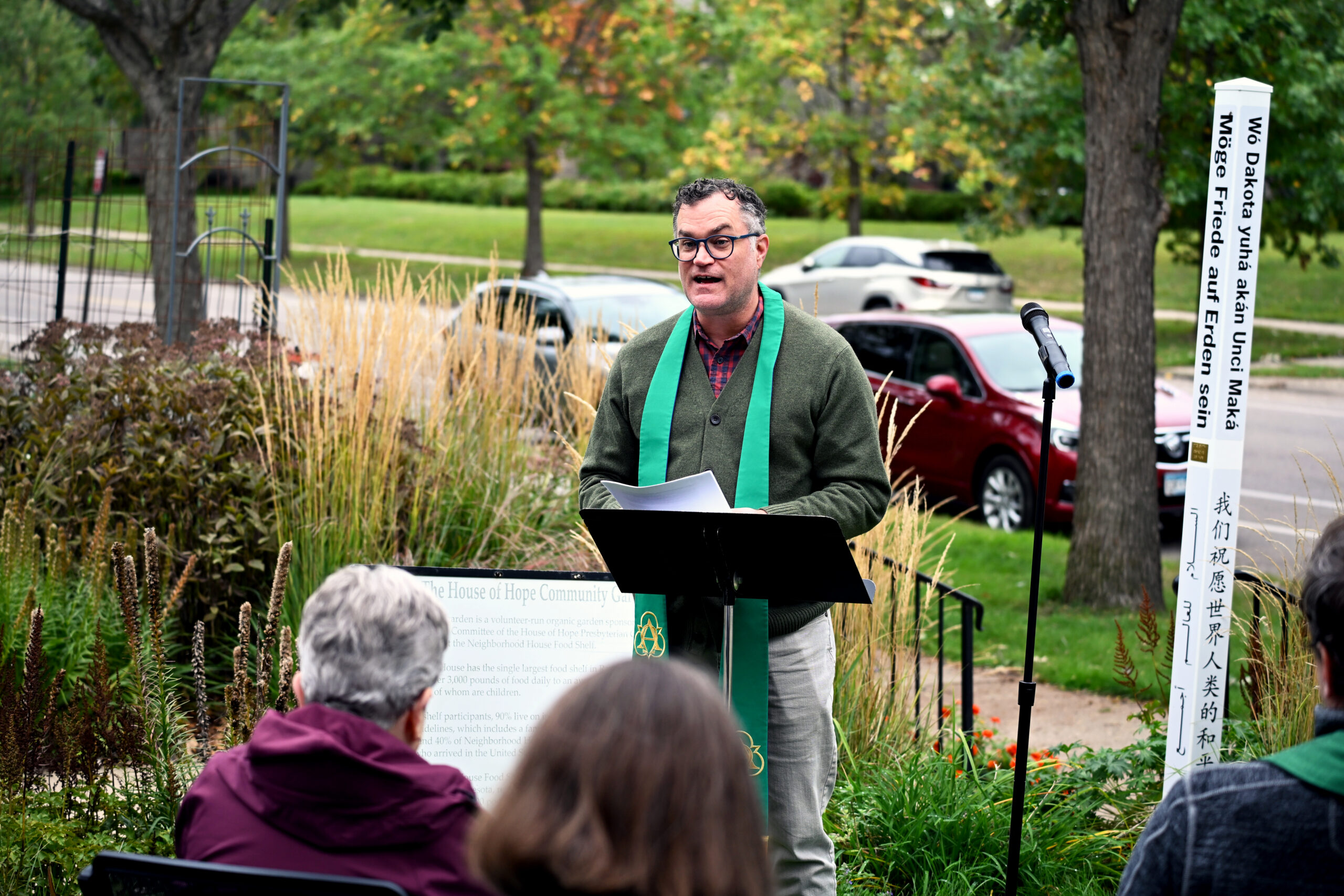 Rev. Dr. Scott Jones reads a statement during the Peace Pole commissioning, with the Peace Pole visible beside him.