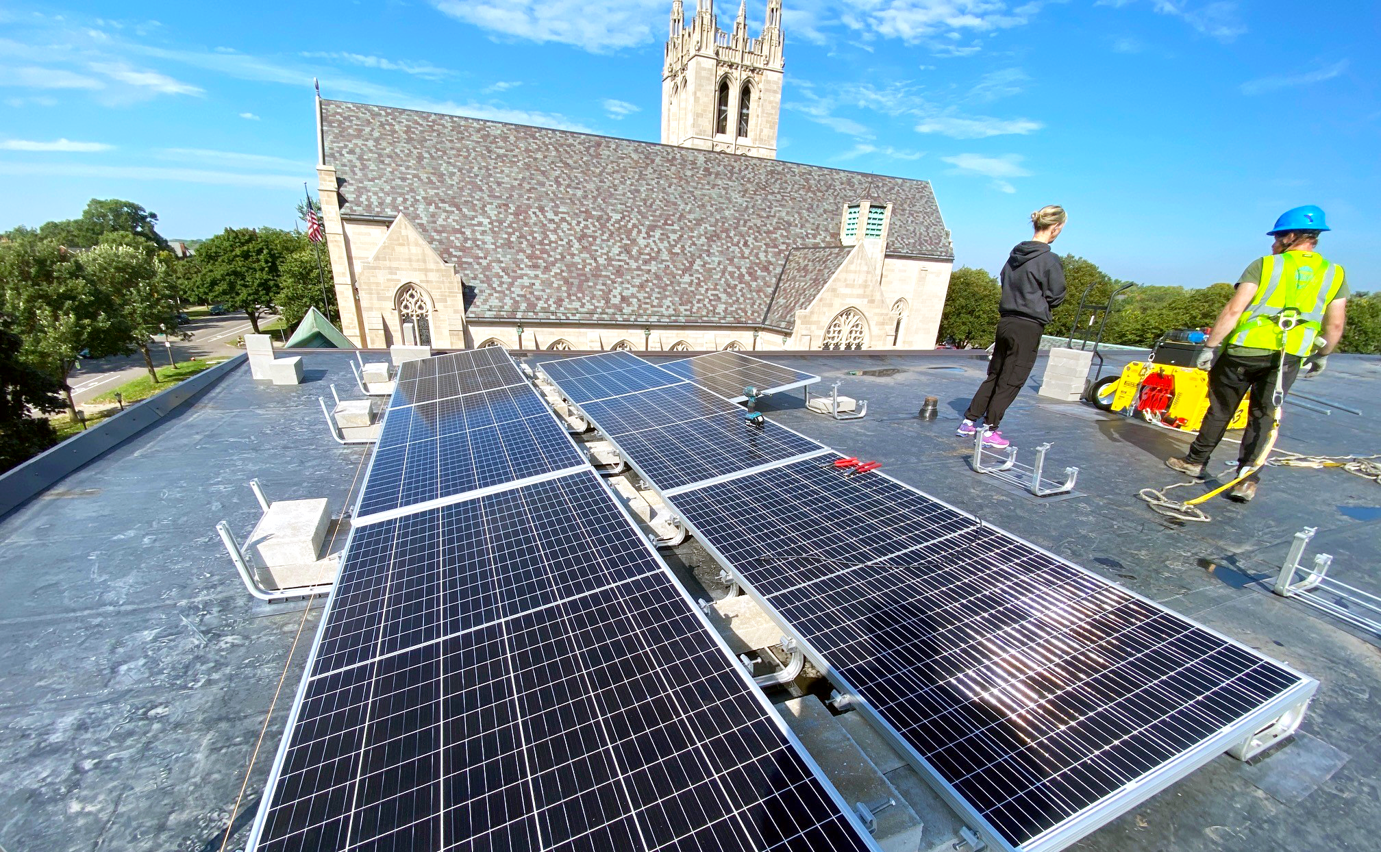 Solar panels and installers on the roof at House of Hope.