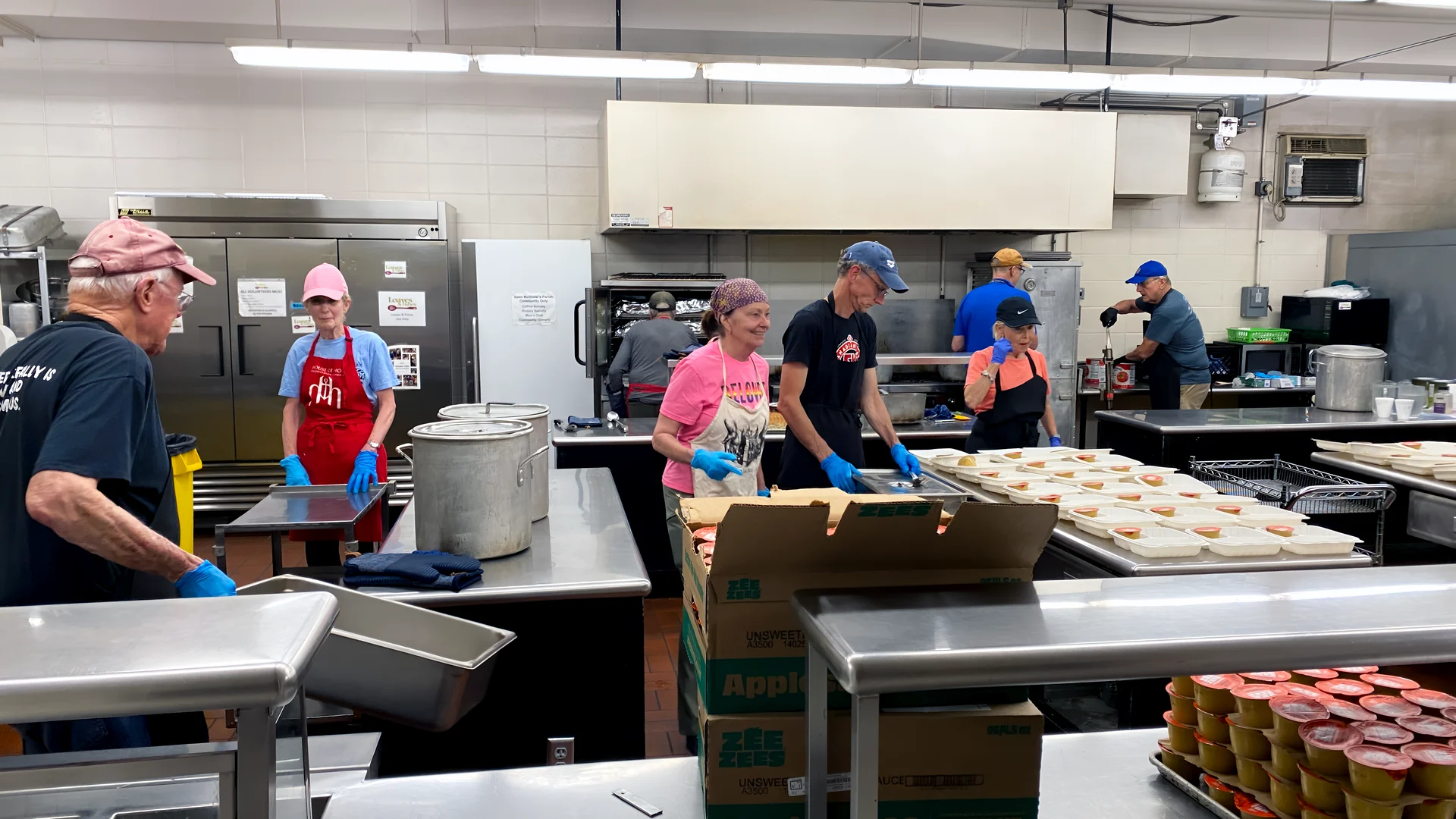 Volunteers preparing and packaging meals in the kitchen.