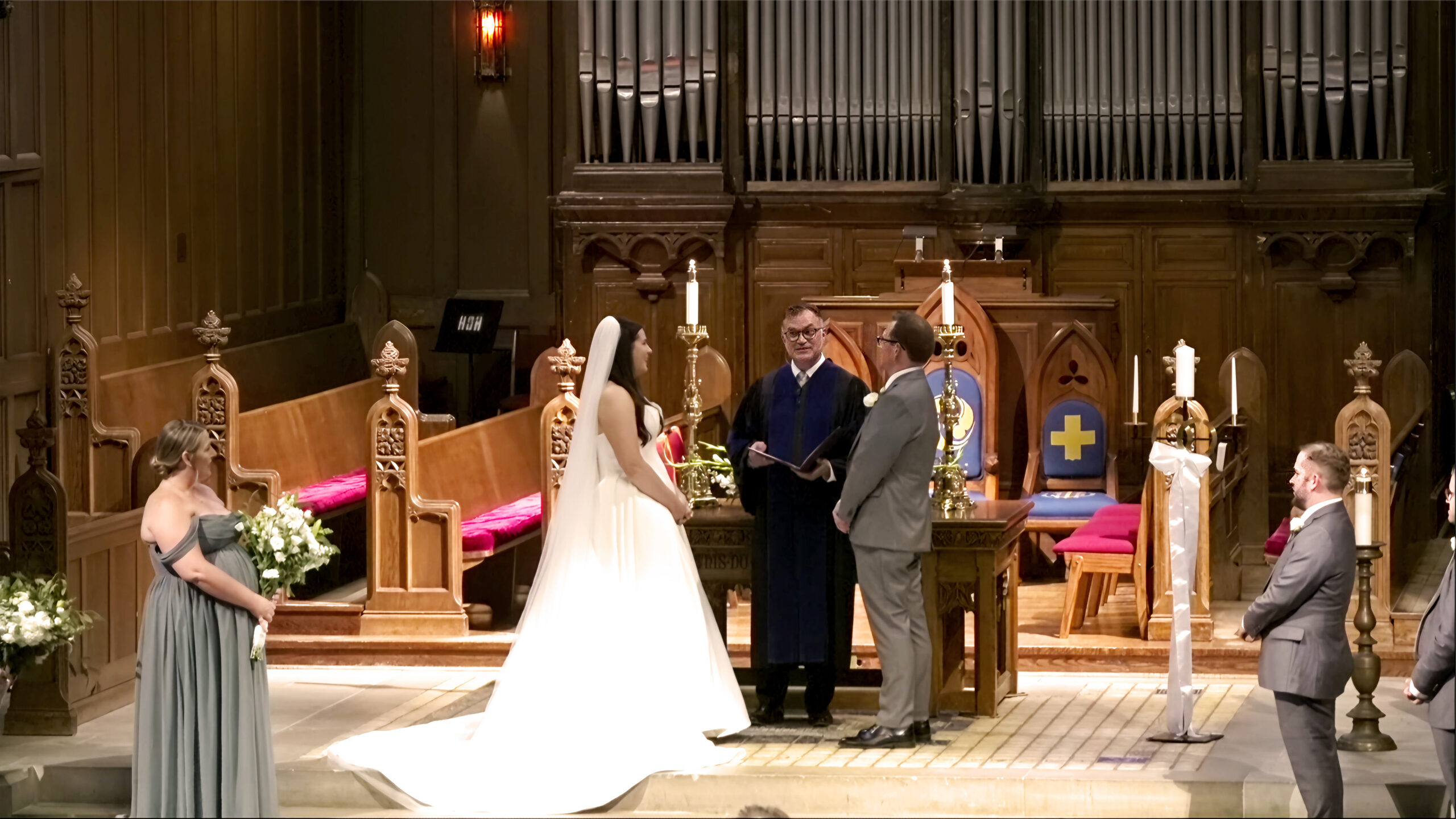 A couple exchanges vows with a minister in the wood-paneled church chancel.